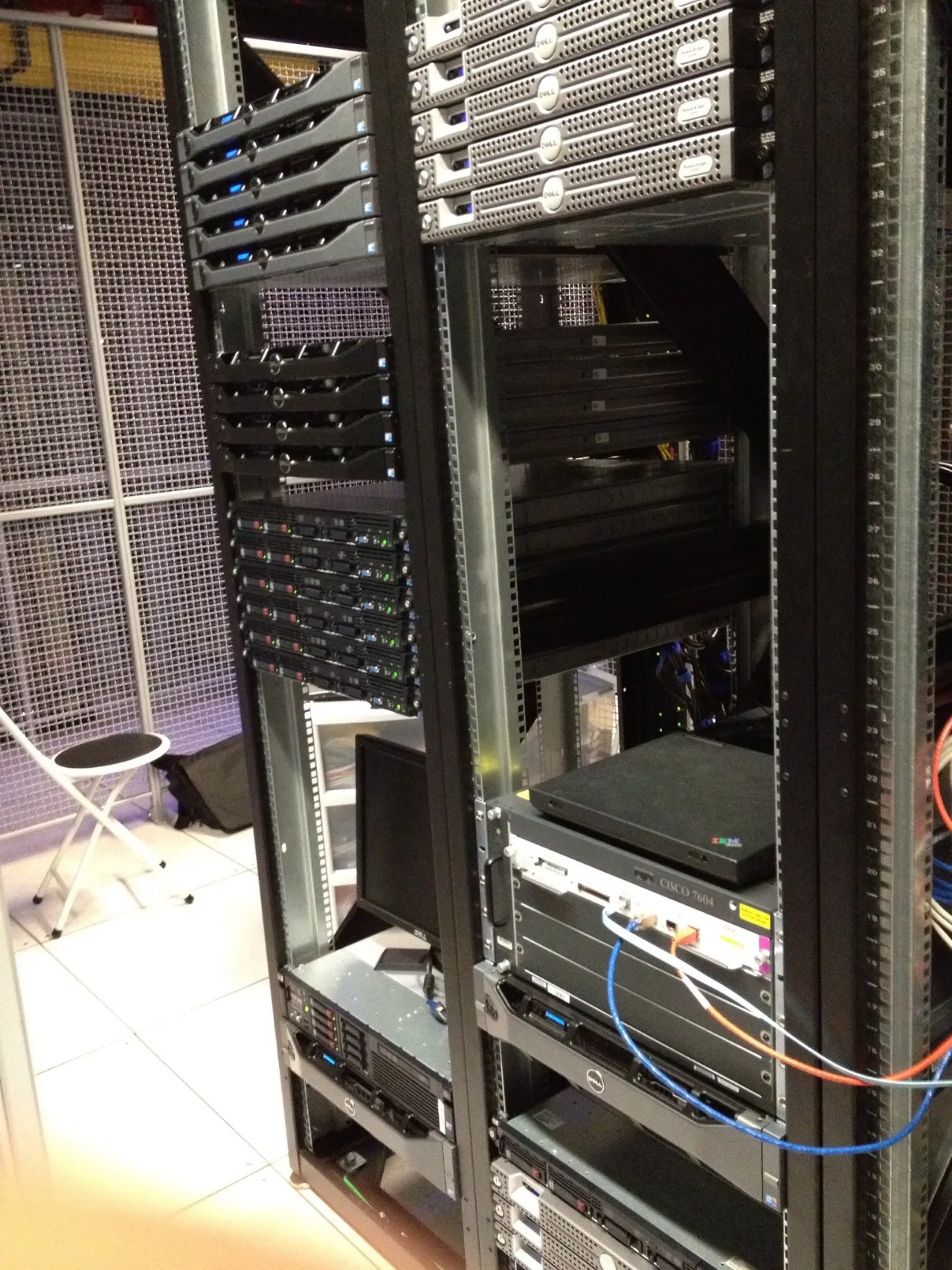Racks of Dell and HP servers with a Cisco 7604 router, a laptop resting on top and a monitor on a lower shelf