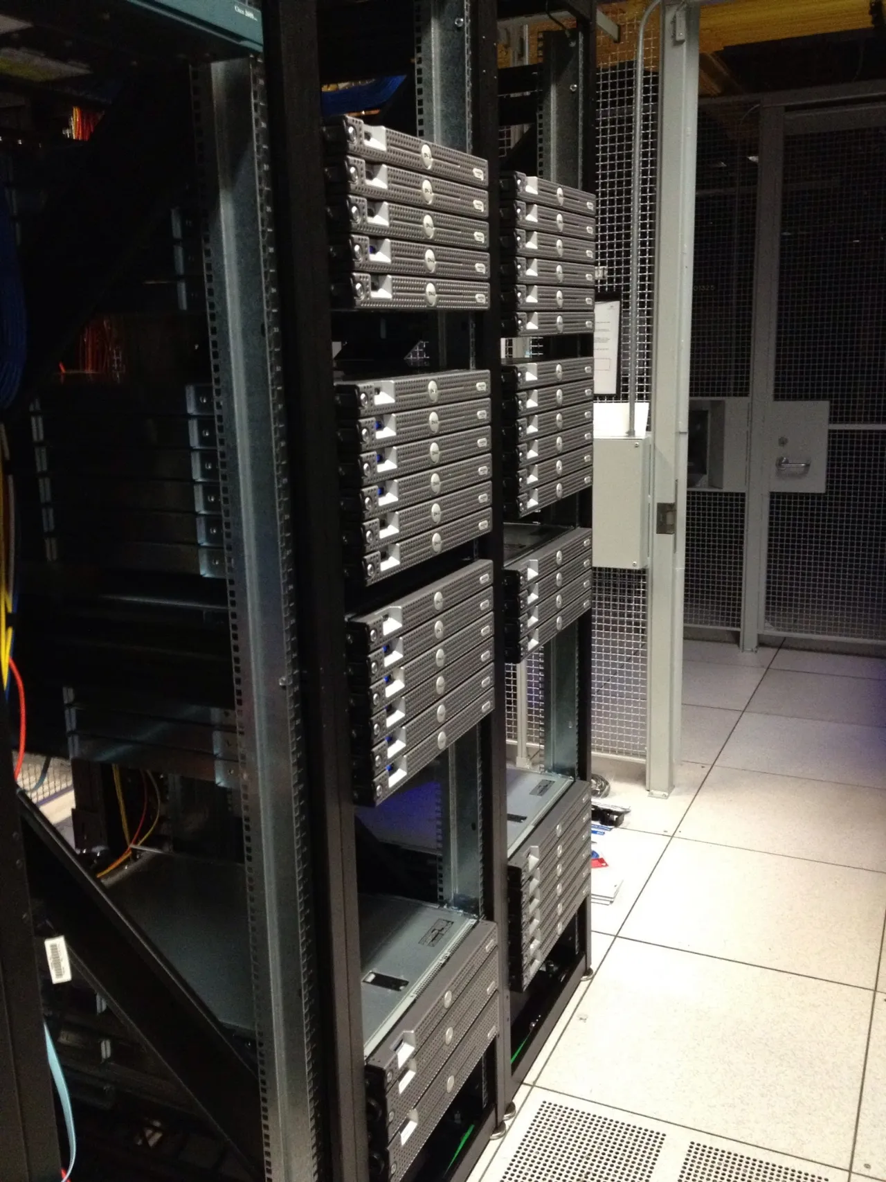 Rows of Dell PowerEdge servers mounted in open racks inside the cage